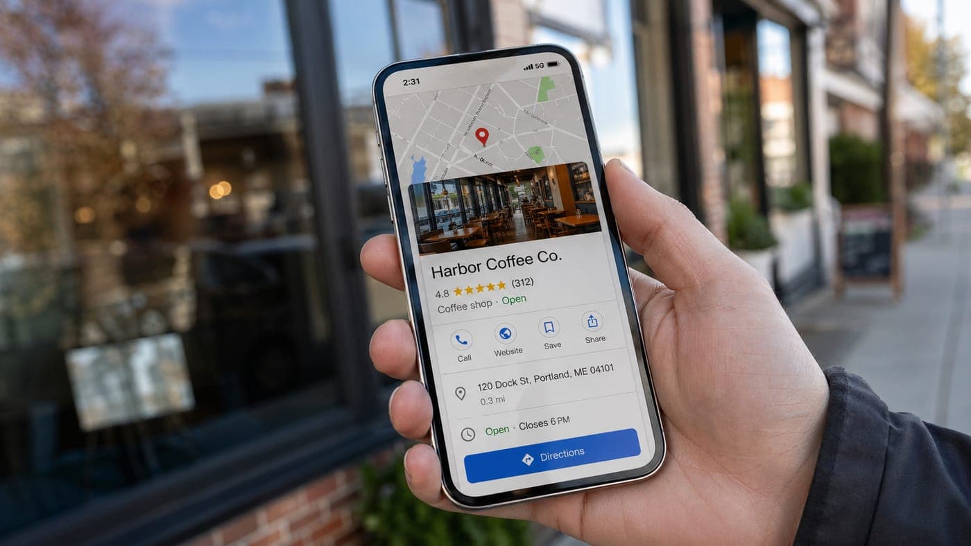 A hand holding a smartphone outside a storefront showing a Google Maps result for a local coffee shop with a 4.8-star rating, address, hours, and a Directions button, illustrating a high-intent local mobile search converting into an in-person visit